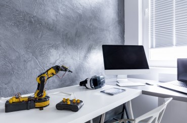 Shot of a big desk with a computer, a robot and VR goggles